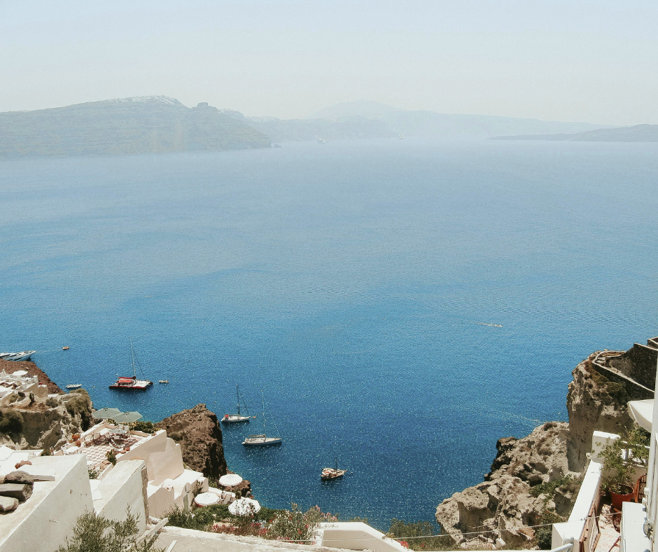 Boats moored in a caldera bay below whitewashed cliffside terraces