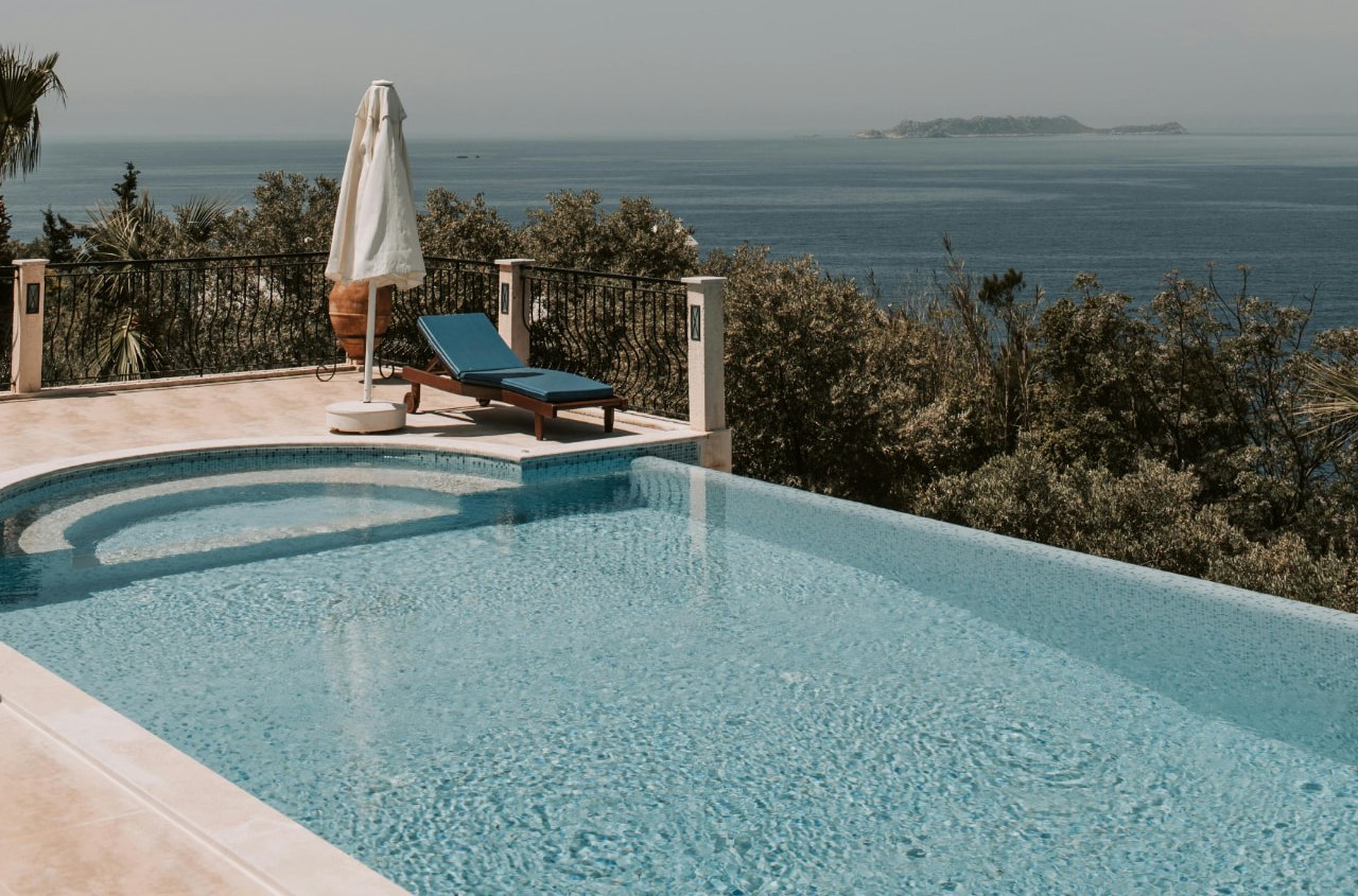 A terrace with a plunge pool, a lounger and a folded umbrella overlooking the sea